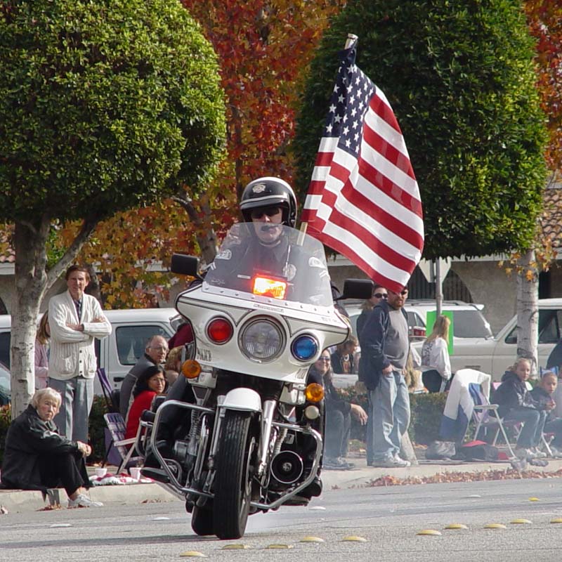 cop on a bike drives while carrying a flag